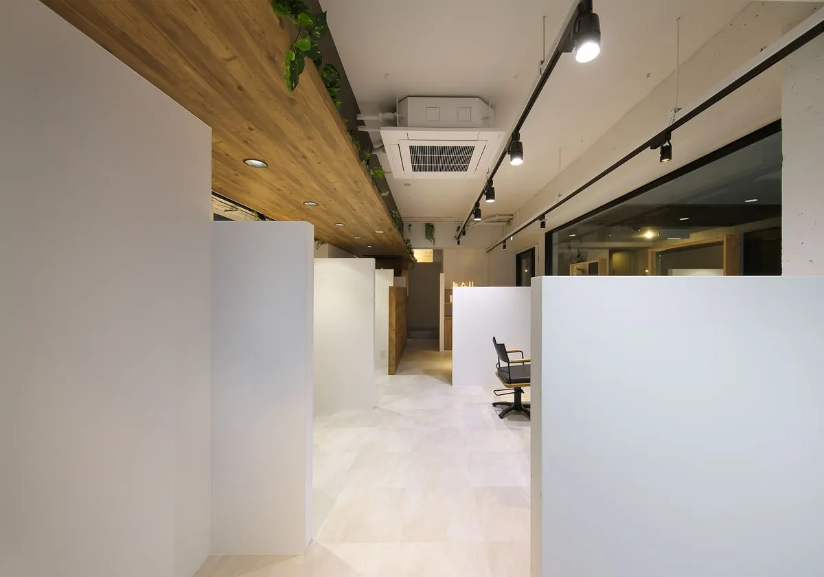 bloom hair design 本店の店内。白い仕切りのあいだの通路が窓の方へ続く