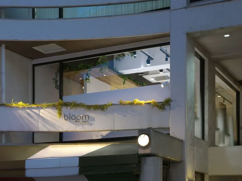 bloom hair design 本店が入るT&Tビルの外観（夕方）。2階の窓の下に bloom のサイン
