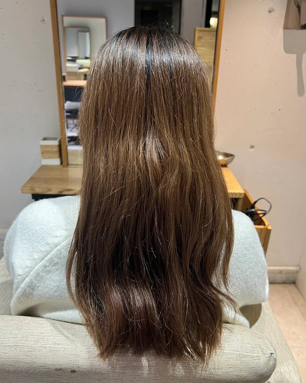 施術前。後ろから見たロング。根元が暗く毛先は明るく色が抜け、毛先がうねるように広がって艶が少ない