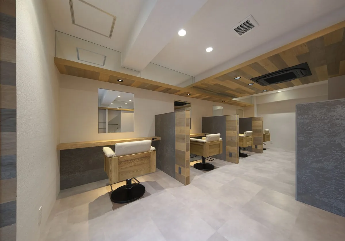 bloom hair design due の店内。グレーと木の仕切りで区切られたセット面が並ぶ